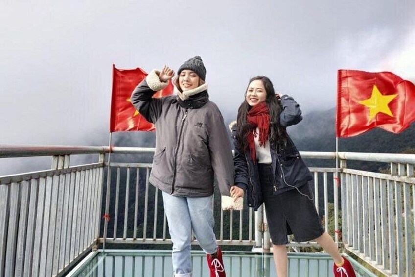 Dos personas de pie sobre un puente, con banderas de Vietnam al fondo. 1