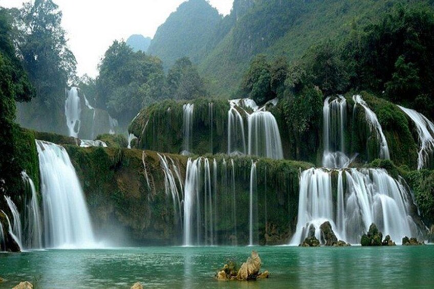 Une cascade d’eau qui dévale des rochers pour se jeter dans un plan d’eau paisible, le tout entouré d’une végétation luxuriante. 3