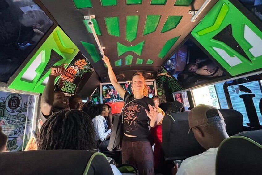 Een businterieur met groene geometrische patronen op het plafond en de muren, en mensen die zitten. 4
