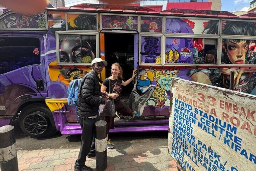 Een paarse bus met graffiti en een bordje ervoor. 3