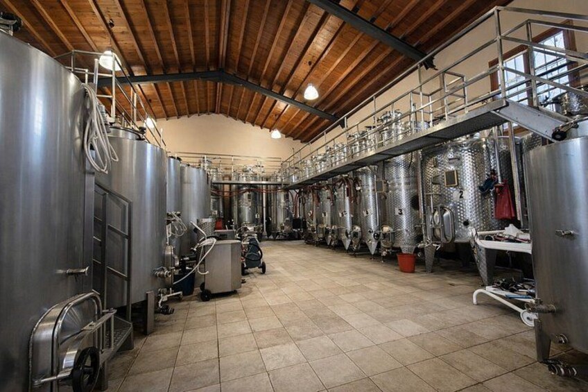 Een brouwerij interieur met roestvrijstalen tanks, houten balken en een betegelde vloer. 3