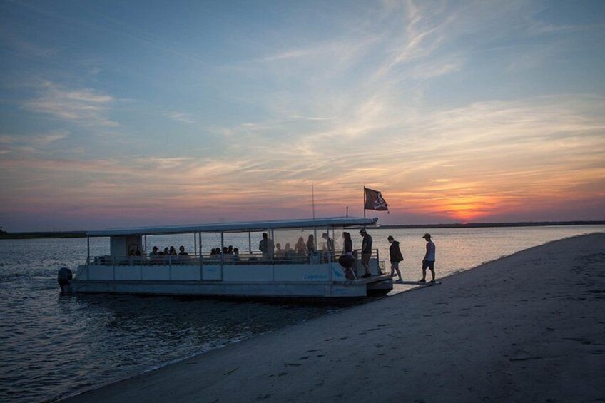 Una barca con persone su una spiaggia al tramonto. 3
