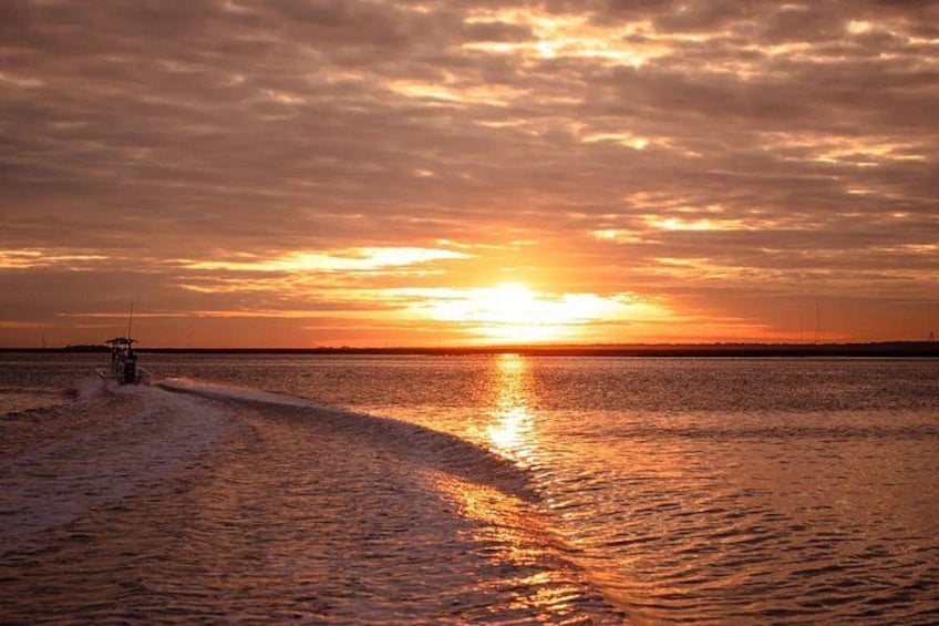 Tramonto su un corpo d'acqua con una barca che solca le onde. 5