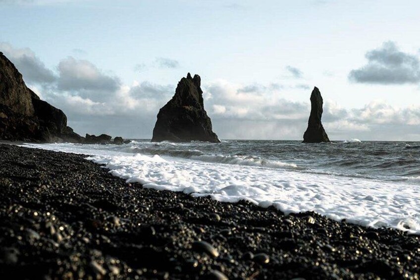 A rocky beach with waves crashing against large rock formations. 5