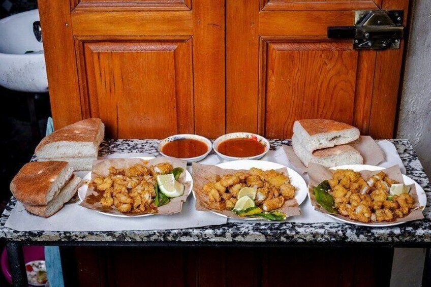 Une table avec du pain, des aliments frits et deux bols de sauce. 5