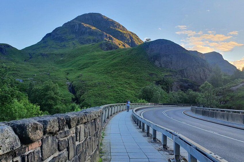Eine kurvenreiche Straße mit einer Steinmauer an einer Seite und einem Berg im Hintergrund. 1