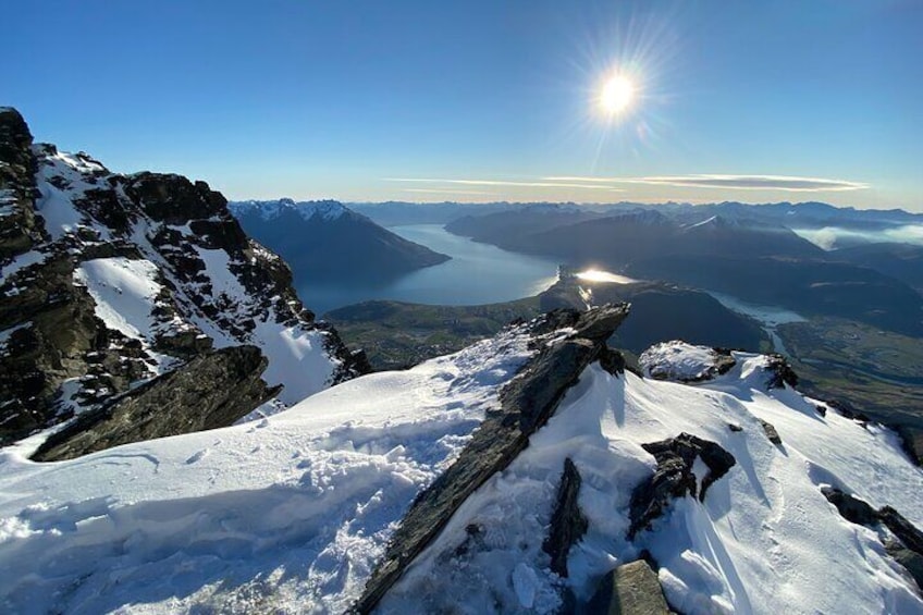 A snow-covered mountain peak with a lake and mountains in the background. 5