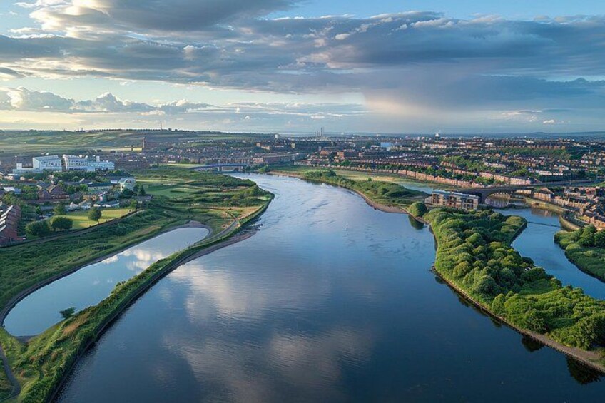 Ein Fluss schlängelt sich durch eine Stadt, gesäumt von Gebäuden und Grünflächen. 3