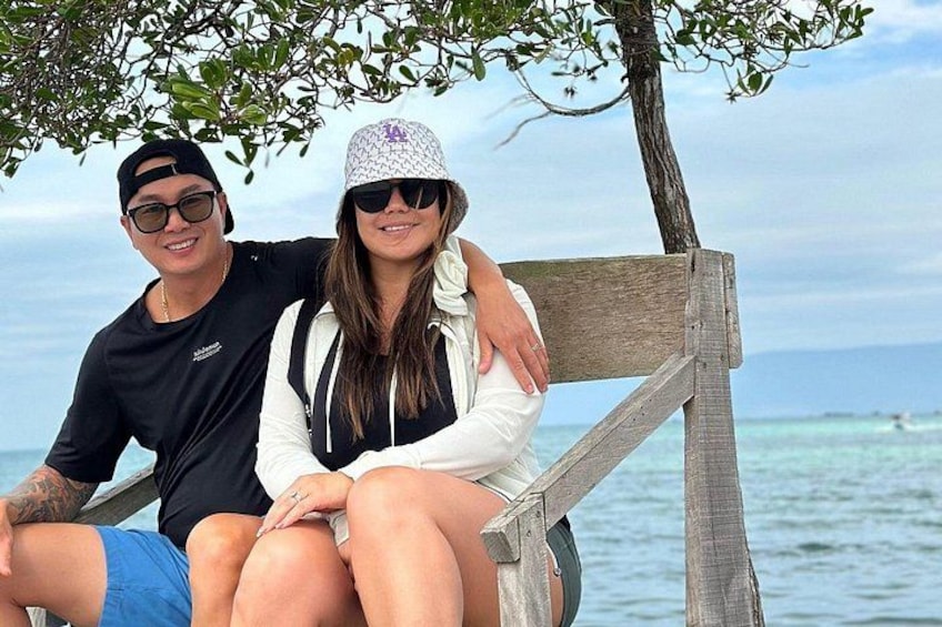 Dos personas sentadas en un banco de madera junto al agua. 4