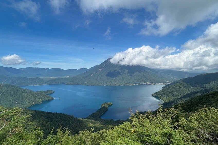A lake surrounded by mountains, clear skies, and lush greenery. 1
