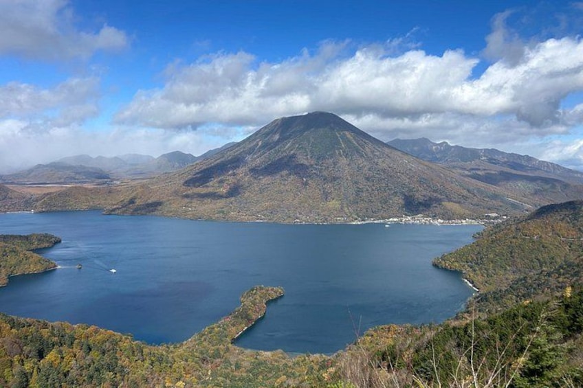 A lake surrounded by mountains, a clear sky, and a small town in the distance. 5