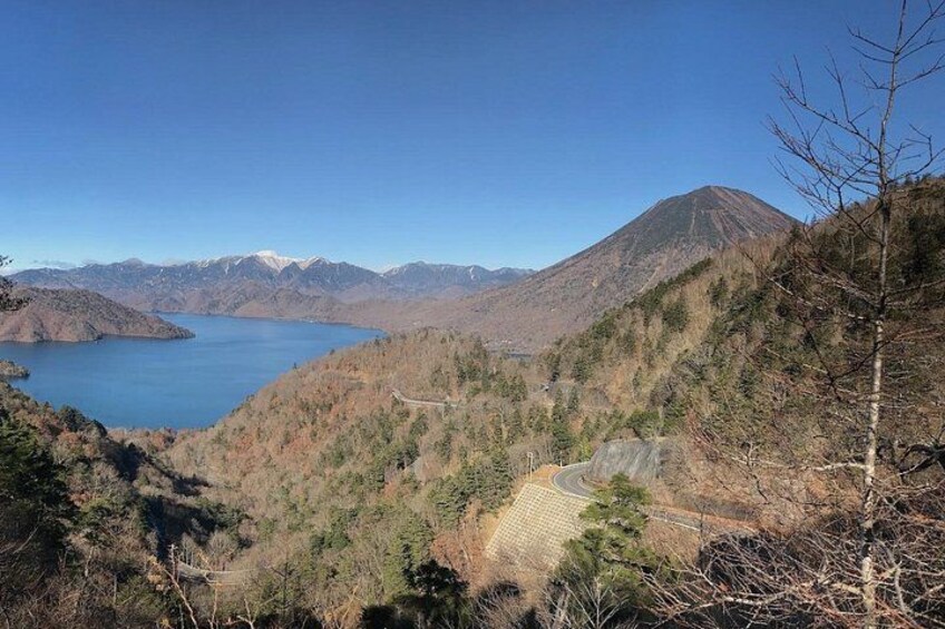 A mountainous landscape with a lake, a winding road, and a clear sky. 2