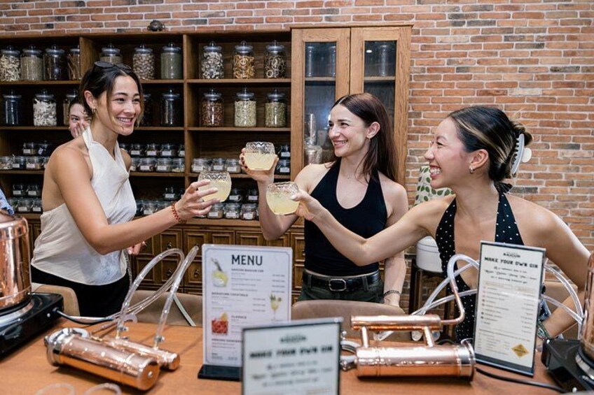Three people at a coffee shop with a menu sign and jars of ingredients in the background. 1