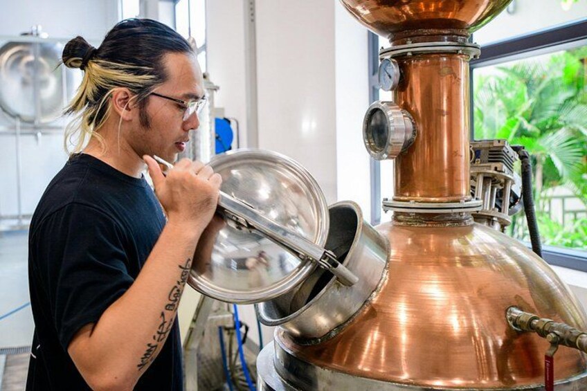 A person inspecting a copper distillation apparatus in a laboratory setting. 4