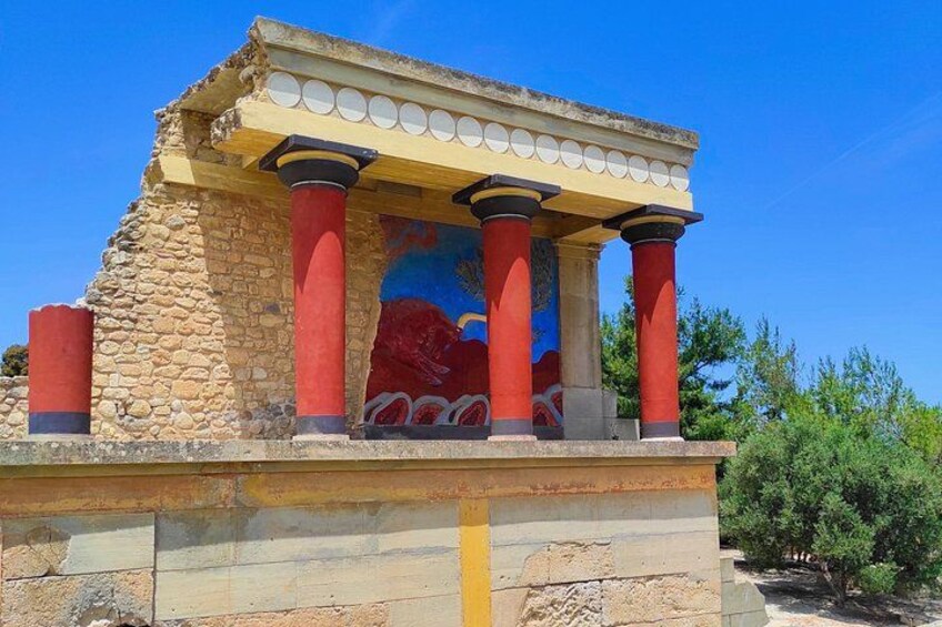 A stone structure with red columns and a painted mural. 1