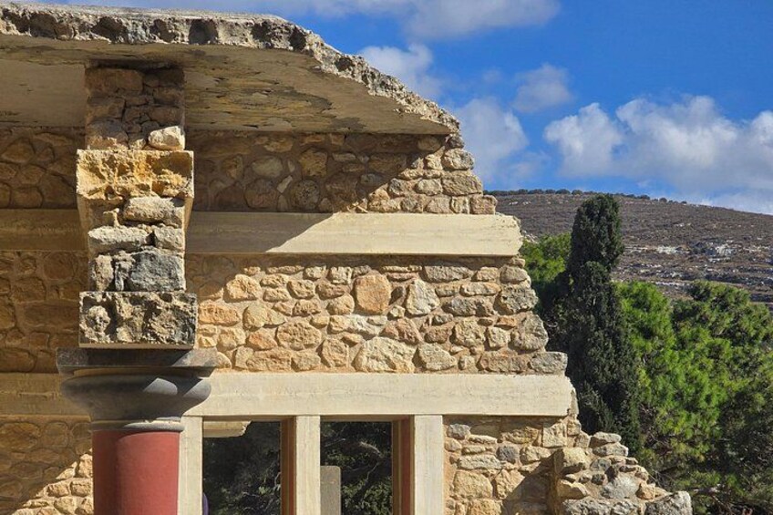 A stone building with a column and a view of a hilly landscape. 5