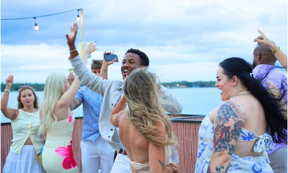 A group of people celebrating outdoors with a body of water and a cloudy sky in the background. 4