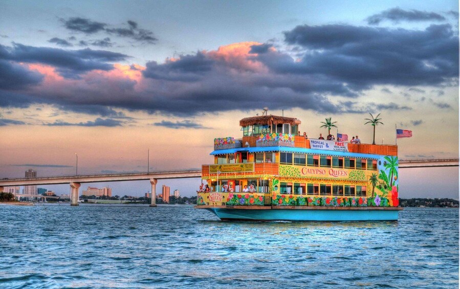 A colorful boat with 'Calypso Queen' written on it, docked near a bridge. 1