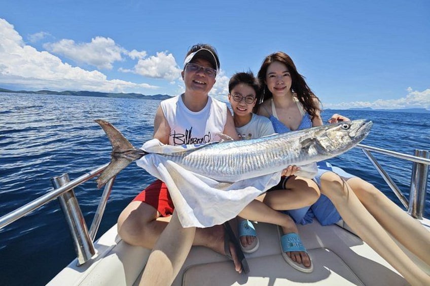 Trois personnes se trouvent dans un bateau et tiennent un gros poisson. 1