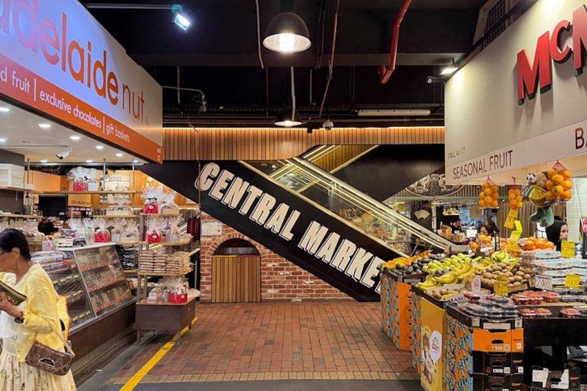L’intérieur d’un centre commercial, avec un espace central aménagé en marché, des stands de restauration et un escalier. 3