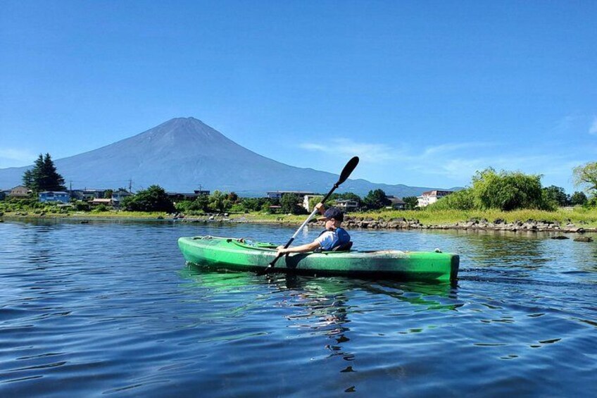 A person kayaking on a calm river with a mountain in the background. 3