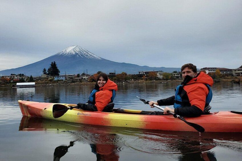 Two people kayaking on a calm lake with a mountain in the background. 2