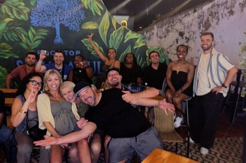 A group of people posing in a room with a mural of a tree and the words 'EDUCATOR' and 'SCHOOL' visible. 4
