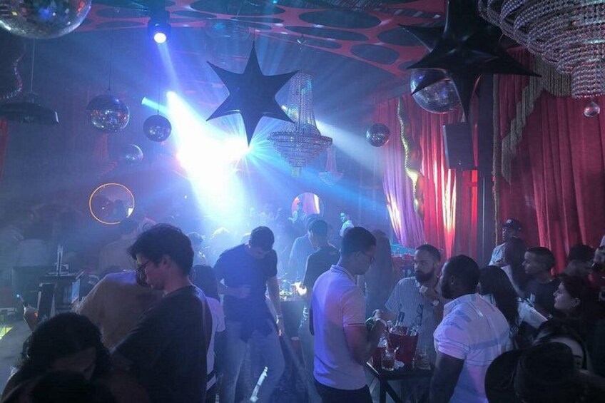 A crowded indoor venue with disco balls and stage lighting. 4