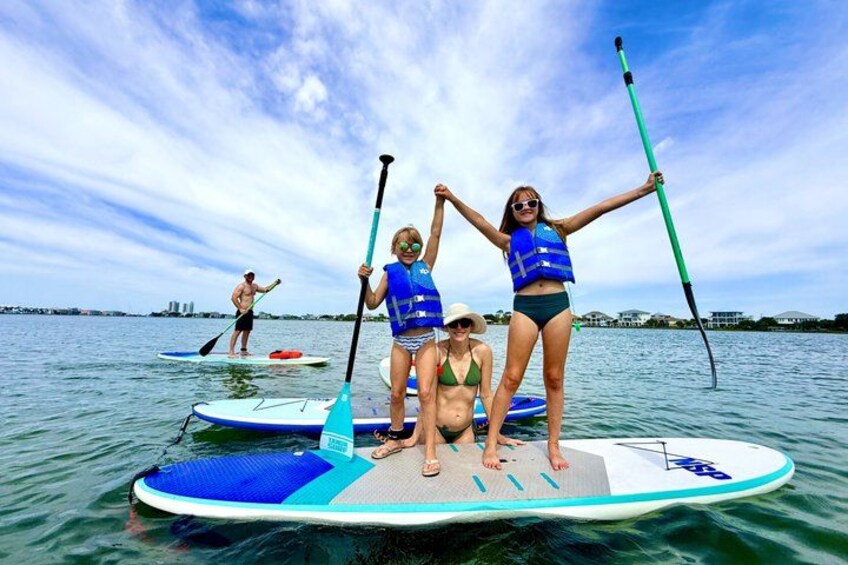 People on paddleboards in a body of water with a city skyline in the background. 1