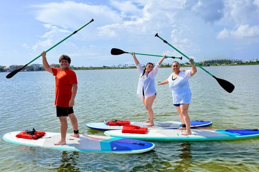 Three people stand-up paddleboarding on calm water with a clear sky. 5