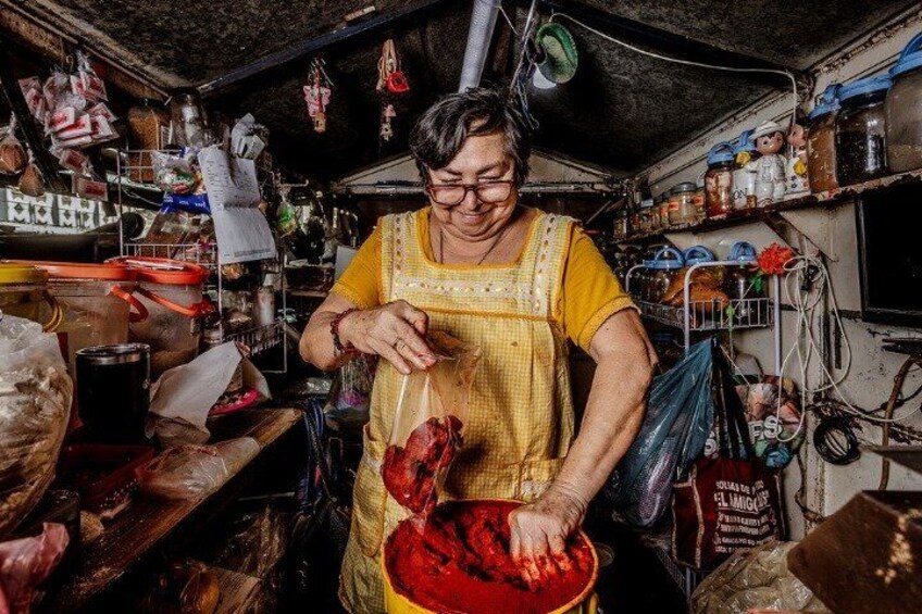 Una persona con un grembiule giallo che maneggia un contenitore rosso in una cucina disordinata. 2