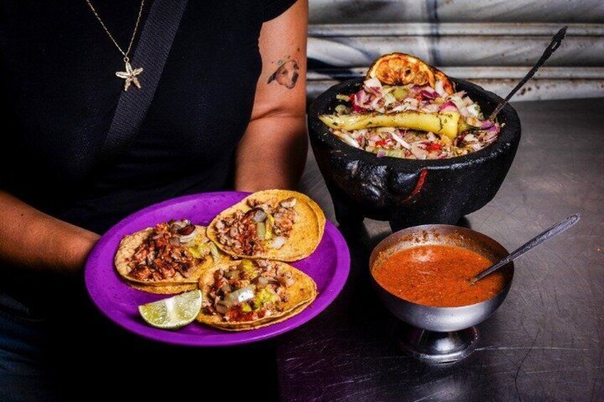 Una persona tiene un piatto viola con tre tacos e una ciotola di salsa. 3