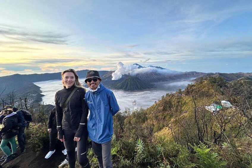 Two people standing on a hill with a mountain and a valley in the background. 2