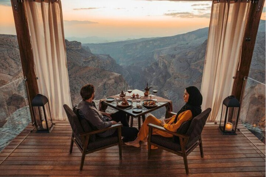 A couple dining at a table with a scenic view of a canyon. 3
