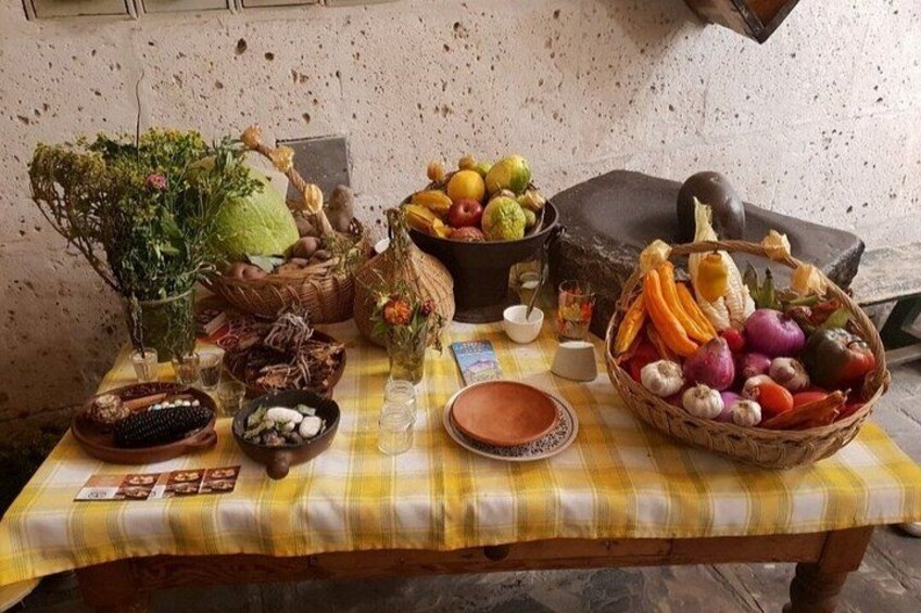 Une table recouverte d’une nappe à carreaux jaunes, avec différents fruits, légumes et un vase rempli de fleurs. 5