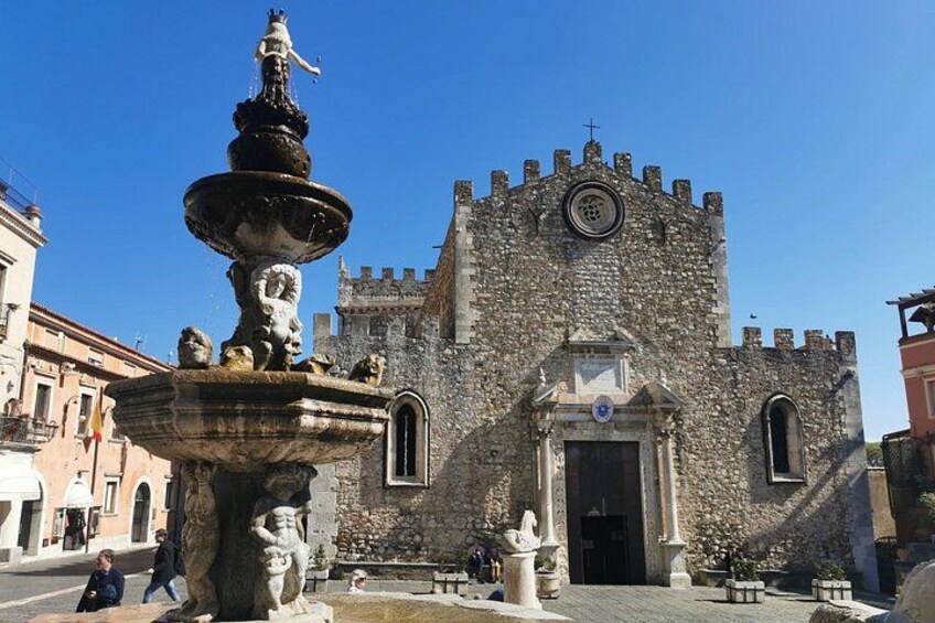 A historic stone building with a large fountain in front. 2