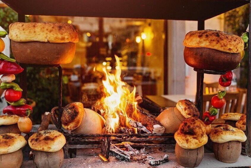 Un horno de leña con pan y verduras asándose sobre fuego abierto. 1