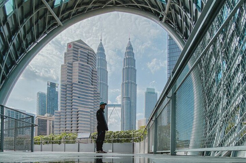 A person standing on a bridge with a view of the Petronas Towers. 1