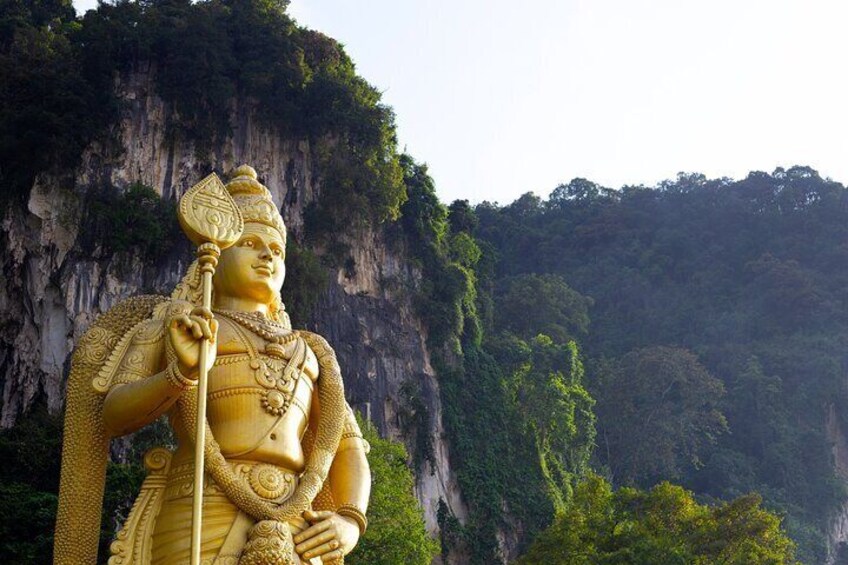 A large golden statue of a deity with a staff, set against a mountainous backdrop. 3