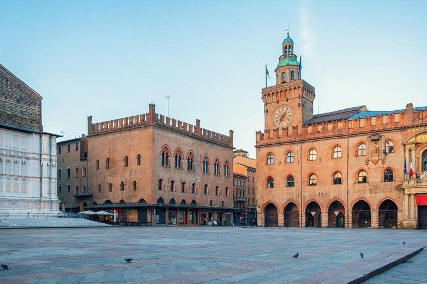 A historic building with a clock tower, arched windows, and a large open plaza. 2