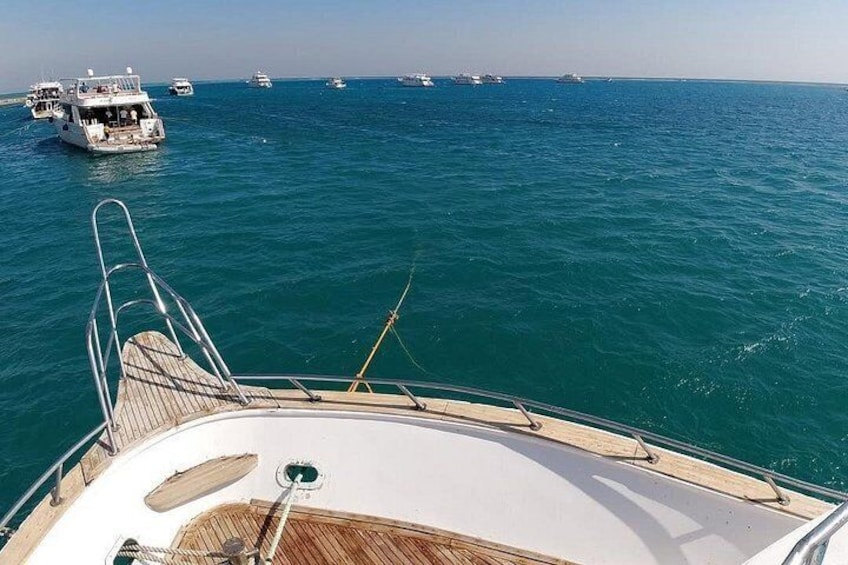 A boat deck with a view of the sea and other boats in the distance. 2