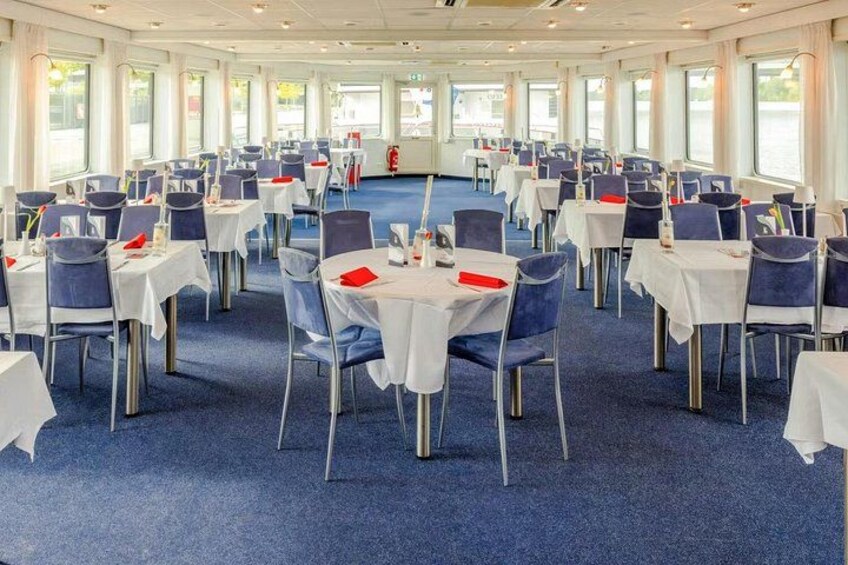 A large, well-lit dining hall with round tables and chairs, arranged in rows. 4