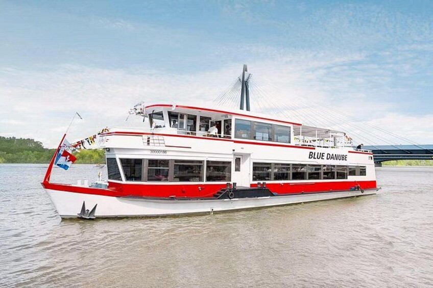 A large white and red river cruise ship named 'BLUE DANUBE' with a bridge in the background. 2