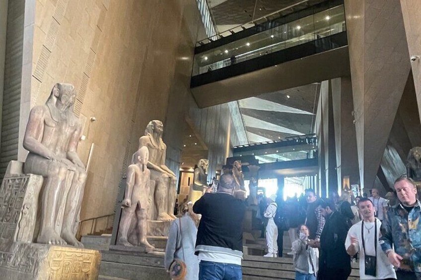 A museum interior with large stone statues and a modern glass ceiling. 5