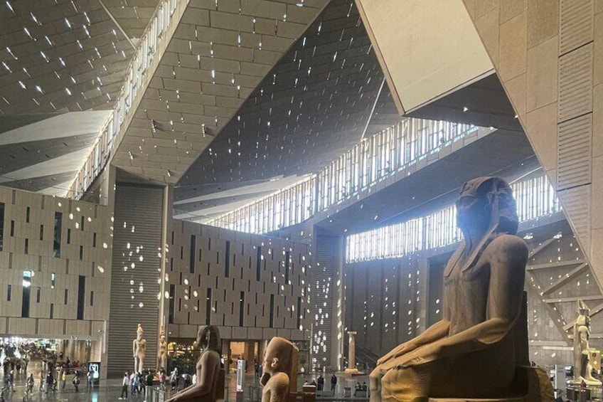 A modern interior with a large statue, geometric patterns on the walls, and a high ceiling with lights. 2