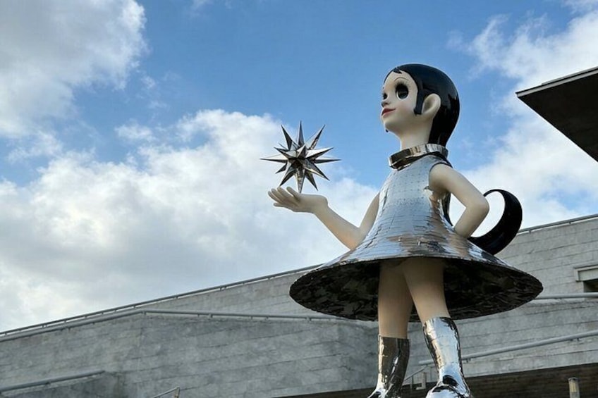 Una estatua de una figura sosteniendo una estrella, sobre un pedestal con un edificio al fondo. 5