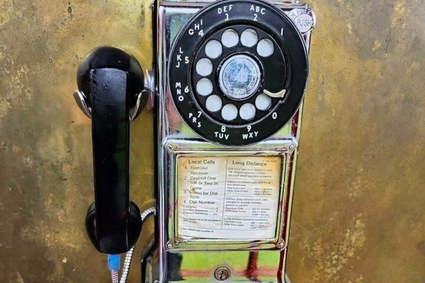 A vintage rotary dial telephone with a metal frame and a glass panel displaying instructions. 4