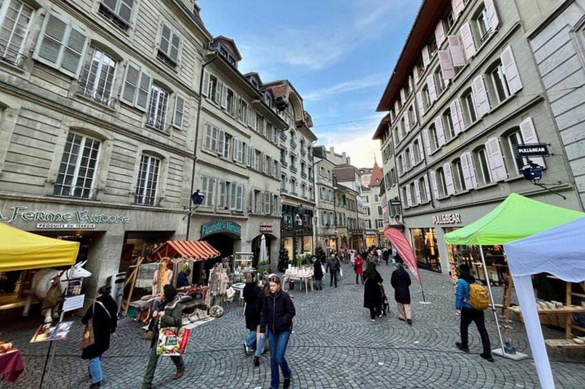 A cobblestone street with pedestrians, market stalls, and historic buildings. 5