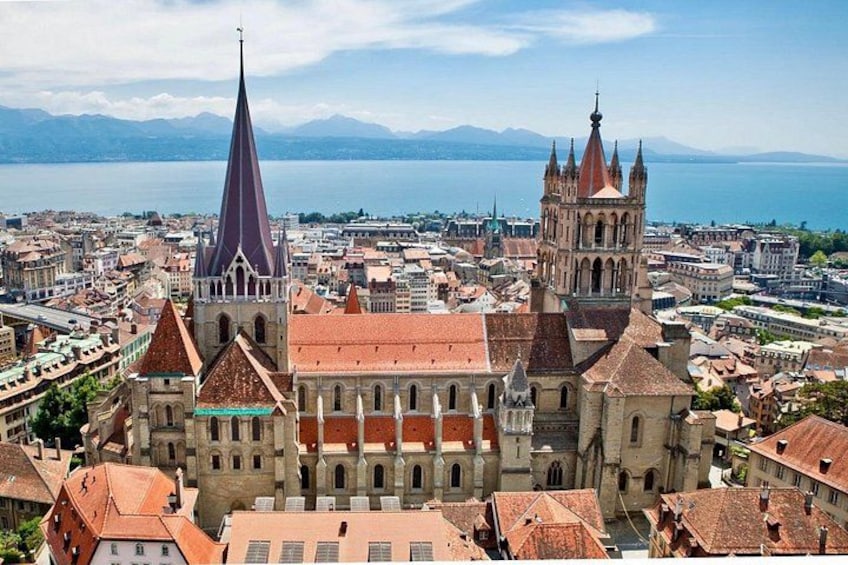 A cityscape with prominent historical buildings, including a church with a tall spire and a cathedral with a red roof. 1