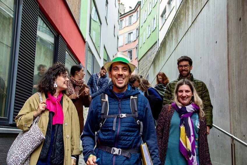 A group of people walking on a narrow street with buildings on either side. 3